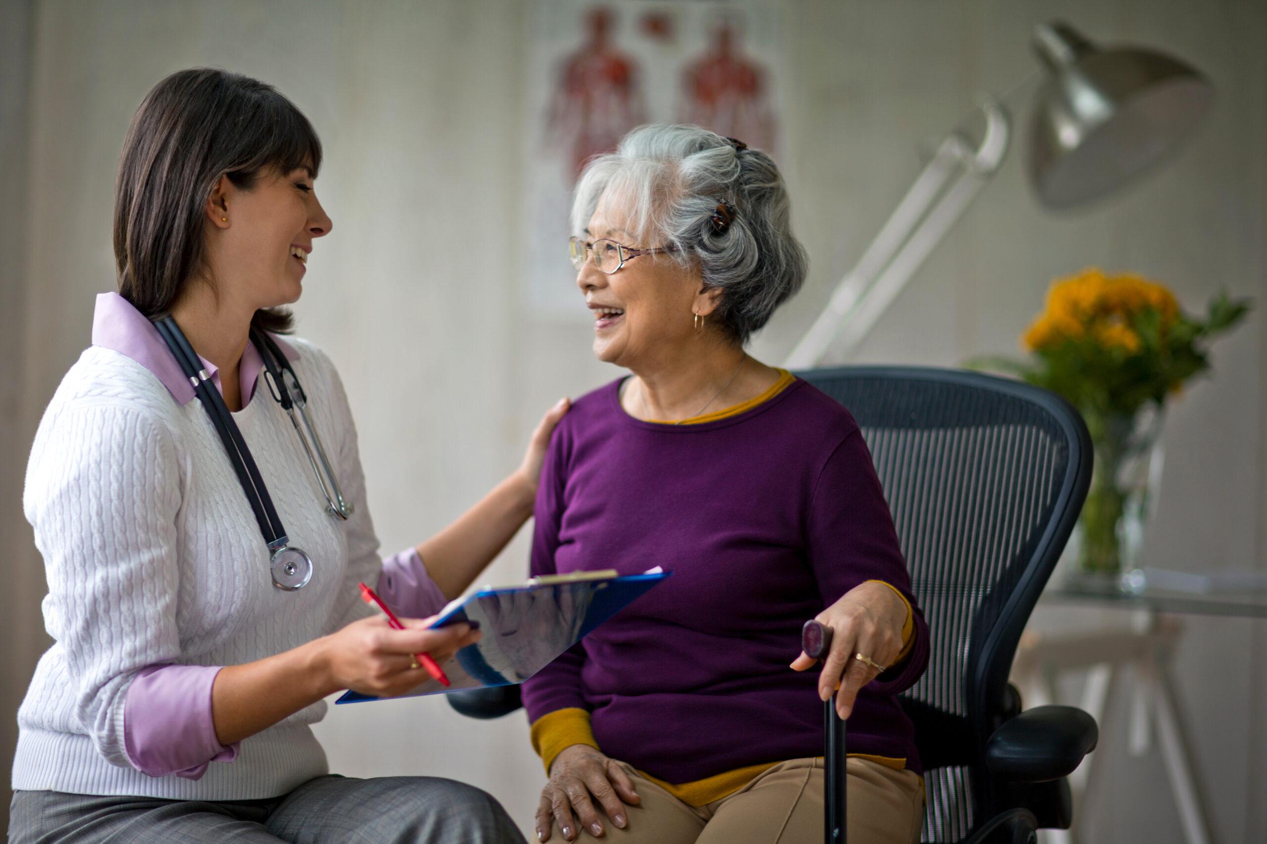 An older woman smiles at a checkup with her doctor.